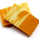 Rahustav apelsini käsitööseep viilutatud seebiplokk kookoskiuga valgel taustal